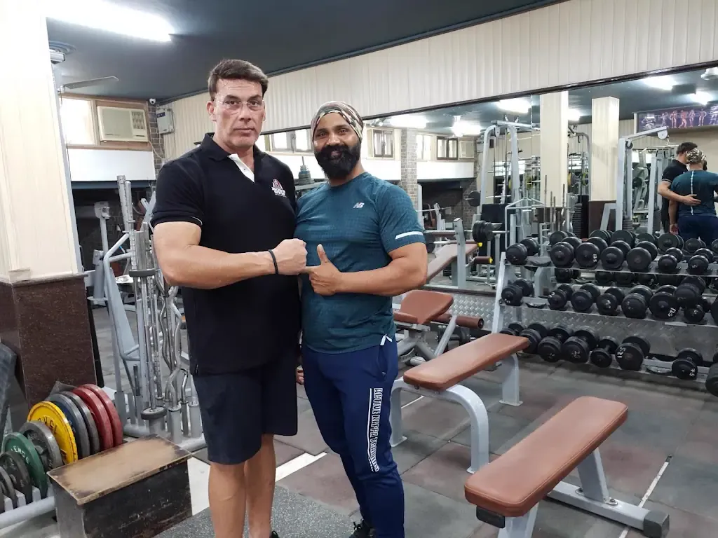Two members at the free-weight and dumbbell rack area, with weight plates and benches